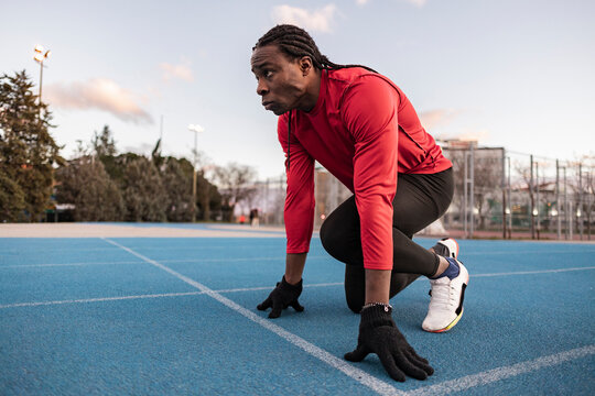 Determined athlete in starting position preparing to run on track