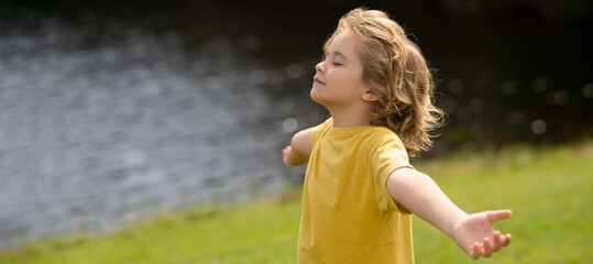 Peaceful kid with raised hands meditating, feeling calm. Kid practice yoga and relaxed on nature....