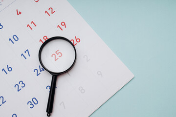 Black magnifying glass and calendar on blue background