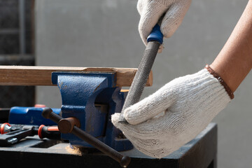 Male hobby retirement. Senior man is using rasp on wood  for assembling hammer handle. - obrazy, fototapety, plakaty