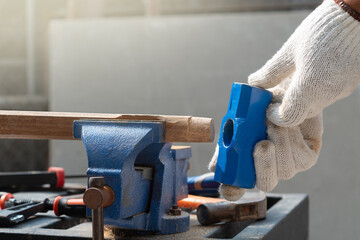 Male hobby retirement. Senior man is using bench vise on wood  for assembling hammer handle.