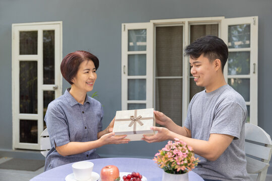 Adult Son Gives A Gift To Mom On The Mother's Day.