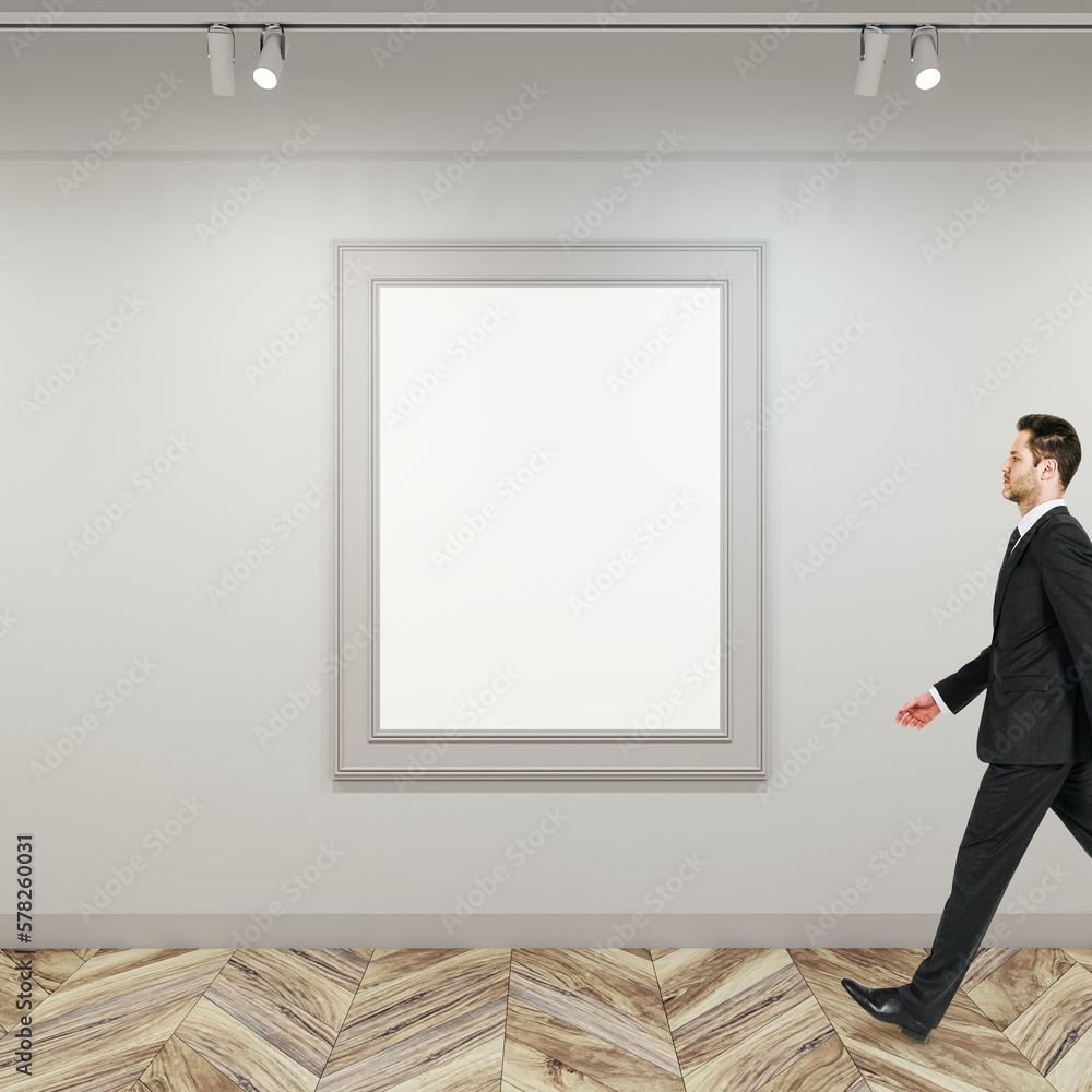 Poster side view of businessman walking in modern gallery interior with empty white mock up poster frame on