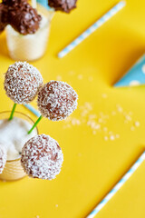 Festival birthday blue boy background with delicious homemade popcake coconut chocolate cake pops on a yellow background, festival desserts, tasty food