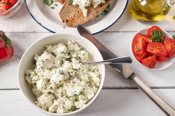 Marinated Feta cheese or sheep cheese with herbs and olive oil served for salad with roasted bread on white table