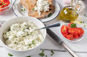 Feta cheese salad with herbs and olive oil. Served with roasted sourdough bread, tomatoes and peppers on a table