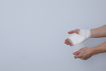 Concept of help during an injury, man wrapping hand in bandage on white background