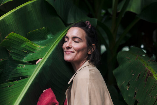 Smiling woman embracing banana leaf