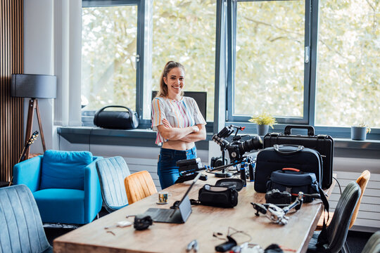 Happy businesswoman with camera and equipment on desk