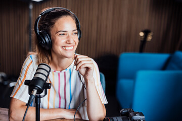 Happy young influencer sitting with microphone in office
