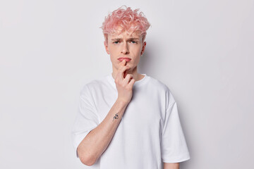 Portrait of displeased pink haired guy looks unhappily or disappointed at camera has grumpy...