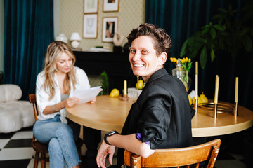 Happy producer sitting on chair with actress in background at film set