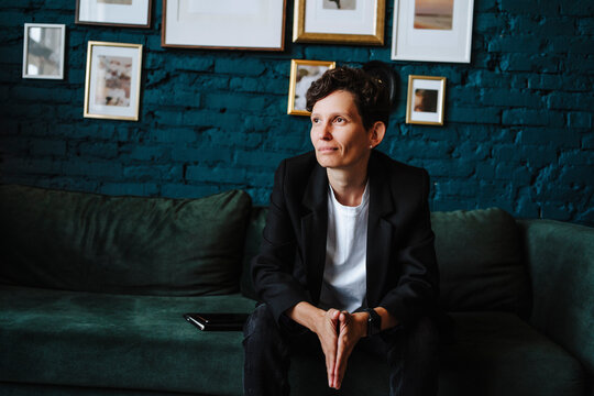 Producer with hands clasped sitting on sofa at film set