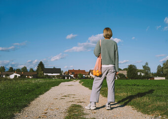 Woman looking at houses standing on footpath