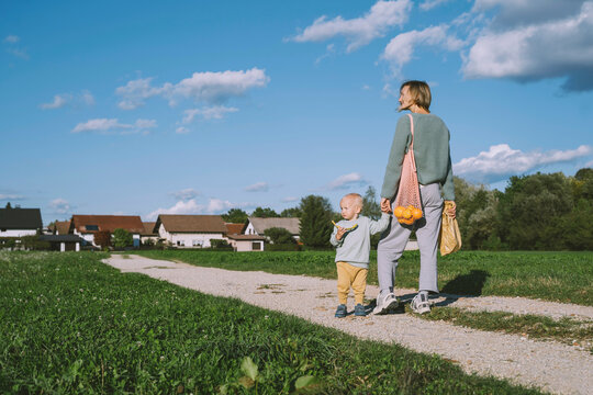 Woman holding hand of son standing on footpath