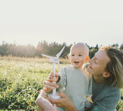 Happy mother playing with son holding wind turbine model