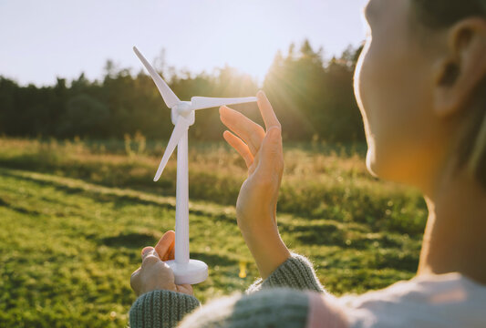 Woman touching wind turbine model on sunny day
