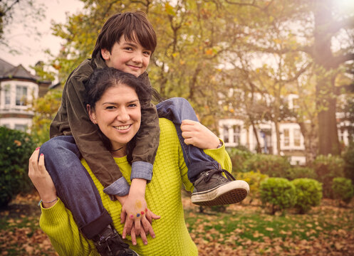 Happy aunt carrying nephew on shoulders at park