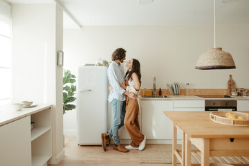 Happy couple standing together in kitchen at home