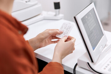Hands of patient holding eye check up result at clinic