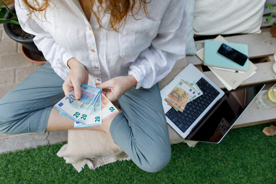 Freelancer with paper currency sitting in backyard