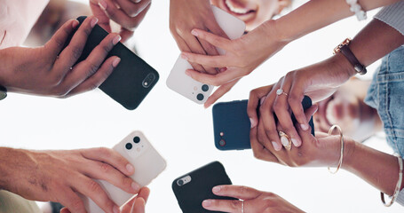Hands, phone and communication with friends standing in a huddle or circle from below for...
