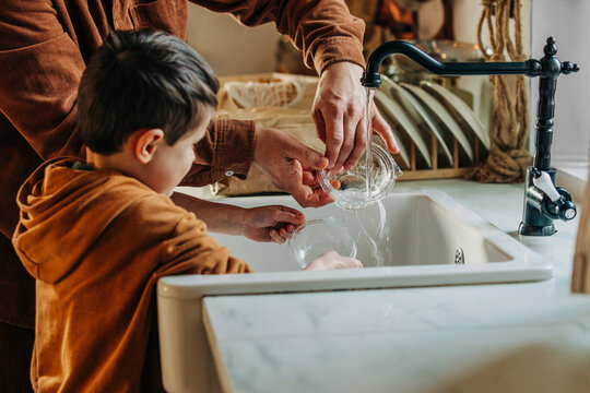 Son helping father in washing plastic container at home