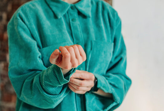 Woman buttoning wrist button of green shirt
