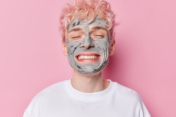 Portrait of cheerful adult man with broad toothy smile keeps eyes closed enjoys skin care beauty...