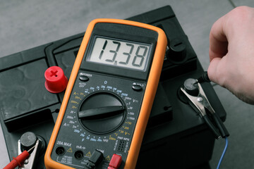 Check and charge car battery with charger. Auto mechanic measures voltage. Voltmeter to check...