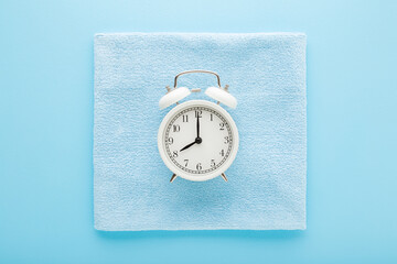 White alarm clock and dry soft microfiber rag for different surfaces wiping. Cleaning time concept....