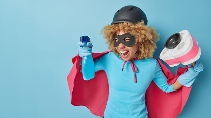 Horizontal shot of emotional woman pretends being superhero does domestic chores brings house in...