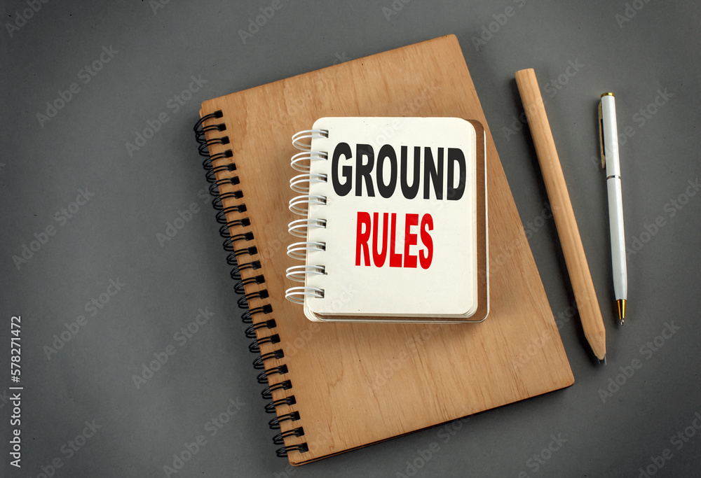 Poster ground rules text on notebook with pen and pencil on grey background