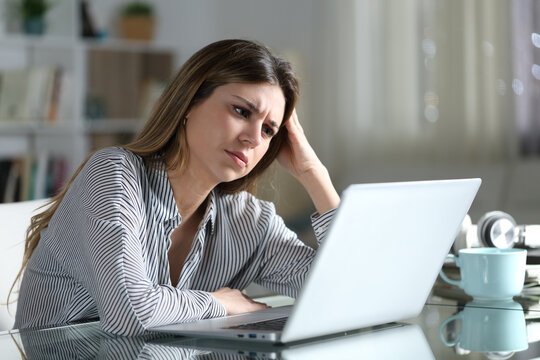 Worried woman is checking laptop content at home