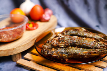 fried mackerel fish served on a plate with spicy sauce