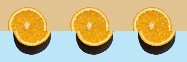 Slices of orange cut in half on bright blue and beige background. Juicy bright citrus fruit close-up. Minimalistic isolated grapefruit