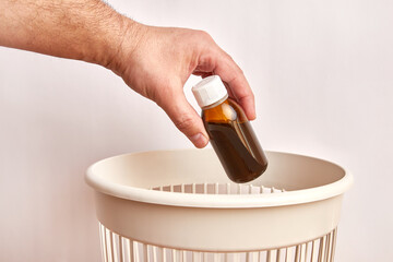 A bottle with an expired medicine is thrown into the trash for disposal and recycling.