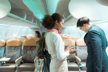 Flight attendant greet passengers as they enter the aircraft to locate a seat in the cabin.