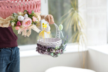 Easter toys. Easter basket with a decorative rabbit in the hands of a man. Blurred background, copy space.