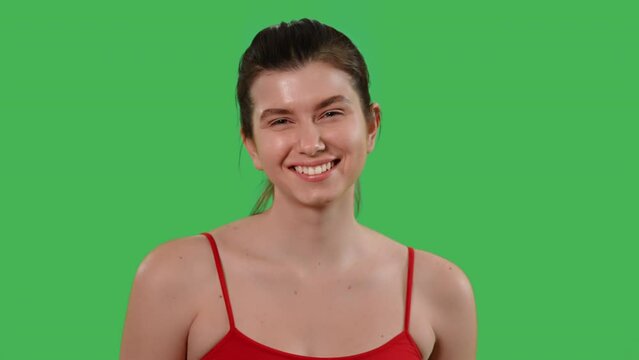 portrait young happy woman looking camera nodding expresses agreement dressed red top Isolated on Green Screen studio