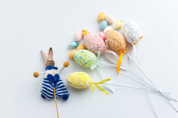Easter toys. Wooden Easter eggs and rabbits on white background, copy space.