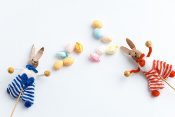 Easter toys. Wooden Easter eggs and rabbits on white background, copy space.