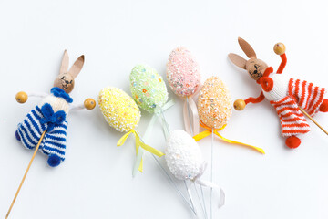 Easter toys. Wooden Easter eggs and rabbits on white background, copy space.