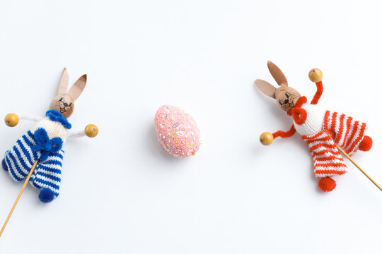 Easter toys. Wooden Easter eggs and rabbits on white background, copy space.