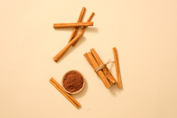 Many cinnamon sticks are displayed with cinnamon powder on a light background. Cinnamon (Cinnamomum) essential oil has a lot of benefits for health