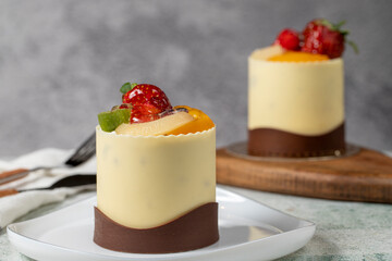 Chocolate and fruit cake. Bakery products. Chocolate covered cake on gray background. Cake made with strawberry, kiwi, raspberry, pear and peach. Close up