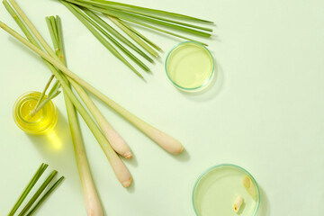 Essential oils on petri dish and glass bottles, fresh lemongrass root and leaves on light...