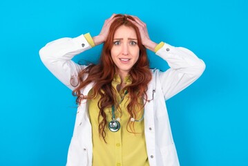 Cheerful overjoyed young doctor woman wearing medical uniform over blue background reacts rising hands over head after receiving great news.