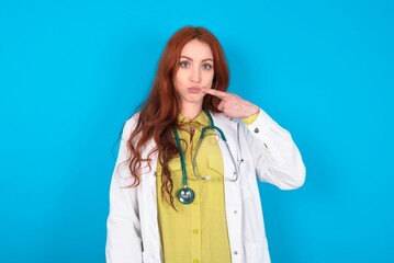 Charming young doctor woman wearing medical uniform over blue background pointing on pout lips with forefinger, showing effect after lifting procedure,