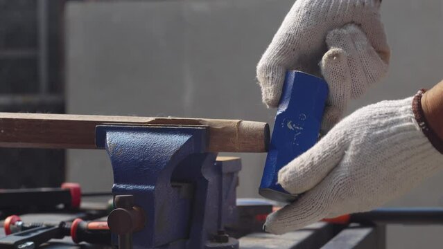 Male hobby retirement. Senior man is using bench vise on wood  for assembling hammer handle.